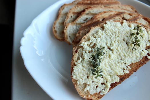 sandwiches from a loaf and with cheese paste on a wooden stand and in a white plate