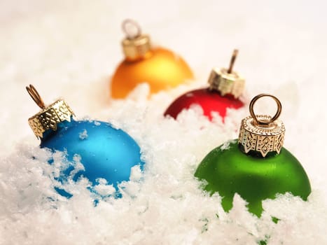 Four old vintage Christmas baubles in snow, seasonal table top with colorful Christmas balls