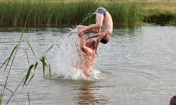 Father teaches his sons to swim and jump into the water, children having fun and having fun on the weekend by the river