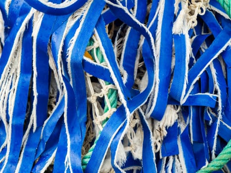 Full-frame close-up view of frayed blue textile ribbons on a ball of fishing nets.