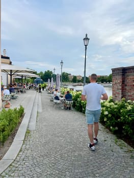 Poland, Wroclaw, summer, July 23. On the terrace over the river, tourists relax at the cafeteria tables on weekends