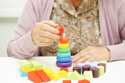 Asian elderly woman playing puzzles game for treatment dementia prevention and Alzheimer disease.