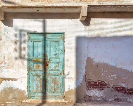 Closed wooden weathered green door and shabby old grunge stone wall on abandoned neighborhood