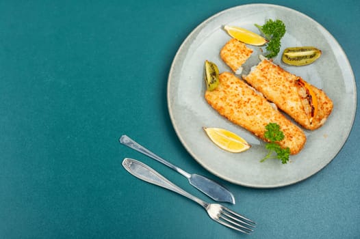 Pollock fillet roasted in bread crumbs and with kiwi. Fish in chips. Copy space.