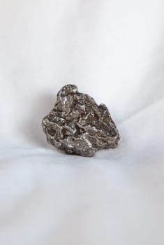 Nickel-iron type meteorite fragment. Placed over cotton cloth