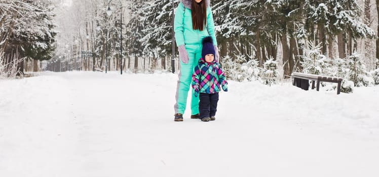 happy family mother and baby girl daughter playing and laughing in winter outdoors in the snow
