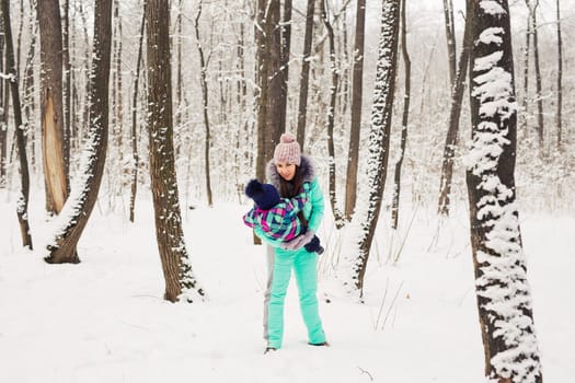 happy mother and baby in winter park. family outdoors. cheerful mommy with her child.