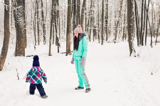 happy mother and baby in winter park. family outdoors. cheerful mommy with her child.