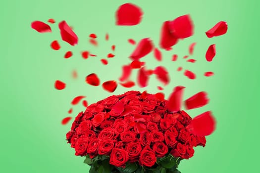 Beautiful bouquet of red roses with flying petals on a green background. Valentine's Day and romance, creative idea. Love