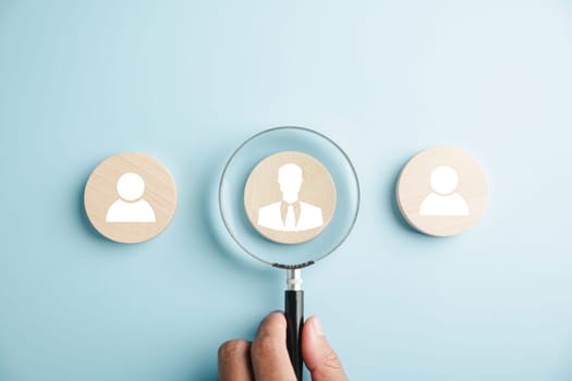 HRM insight Magnifier glass zooms in on manager icon in staff icons, representing the valuable role of human resource management in recruitment, leadership, and customer targeting. employees selection