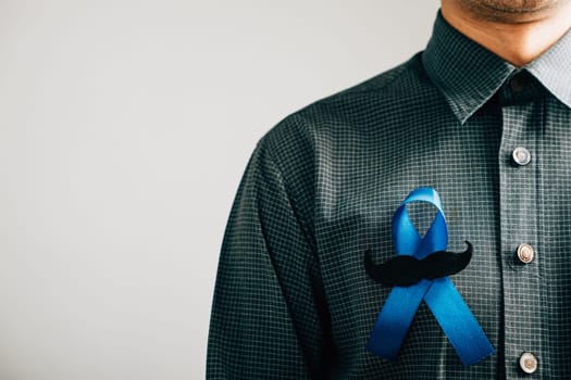 A powerful symbol of support, men's hands hold a Blue Ribbon with a moustache, representing awareness for Colon cancer, Colorectal cancer, Child Abuse, world diabetes day, and International Men's Day.