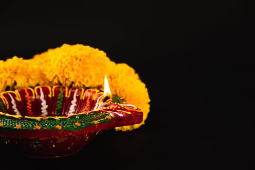 Celebrate Indian Festival Diwali, A beautifully crafted Diwali lamp and intricate flower rangoli adorning a dramatic black background. Ideal for Diwali invitations, weddings, and religious ceremonies.