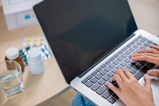 Sick young woman sit on sofa video call online with laptop consult with doctor at home, female covered blanket checking medications online, healthcare and technology