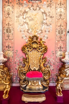 Isola Bella, Italy - 1 August 2023: antique throne in gold and red velvet. Old royal chair, luxury vintage.