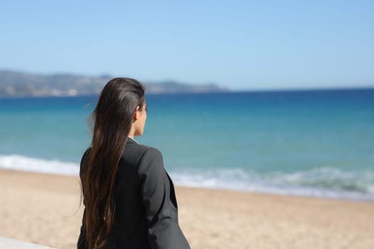 Single executive relaxing contemplating ocean sitting on the beach