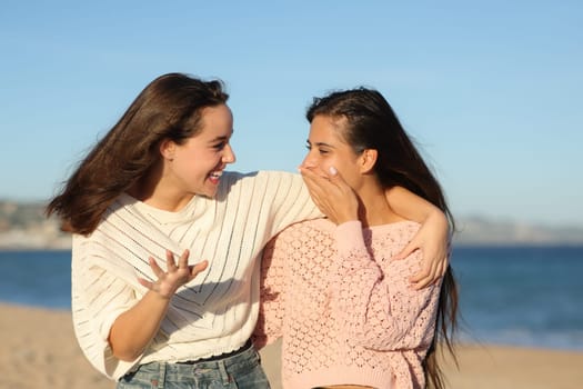 Gossip friends talking and telling surprising anecdote on the beach