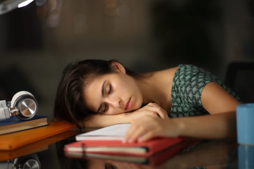 Tired overworked student sleeping over notes in the night at home