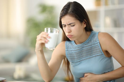Woman suffering belly ache drinking milk at home