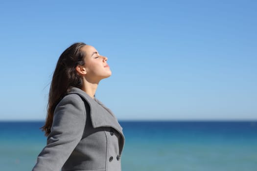 Side view portrait of a relaxed woman in winter breathing fresh air on the beach