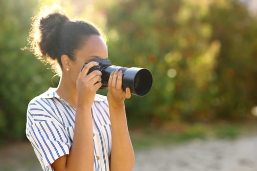 Black photographer taking photos standing in a park