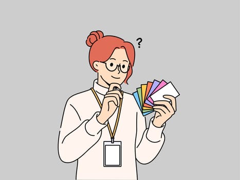 Woman designer holds palette of cards of different colors, choosing desired shade to use in design. Business girl working as designer makes decision on choosing main color for corporate identity