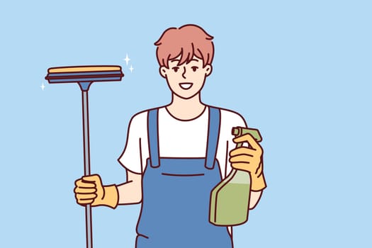Happy man window cleaner holds spray bottle with detergent and mop for cleaning glass and glossy surfaces. Professional janitor provides window cleaning services in business centers and offices