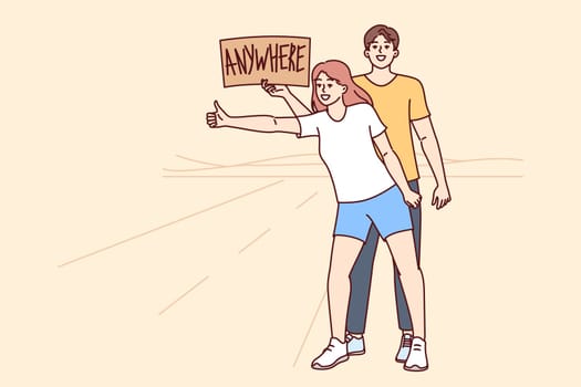 Man and woman hitchhike and catch car standing at road, holding inscription anywhere in hands. Carefree couple went on hitchhike trips, in search of adventure and new positive emotions.