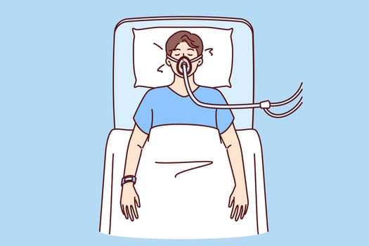 Sick man lies unconscious in hospital bed and receives air through ventilator due to heart attack. Sick guy in serious condition after surgery, and removal of cancerous tumor from body
