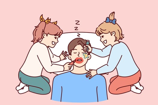 Funny little girls make up sleeping father by painting on man face with lipstick and colored markers. Two cheerful preteen daughters play pranks and laugh father sleeps after work.