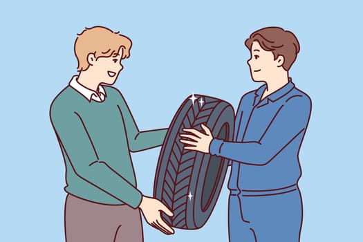 Man buys new tires for car wheel and consults mechanic, who help make right choice. Casual guy purchases winter tires for wheels to protect himself and those around from car accident.