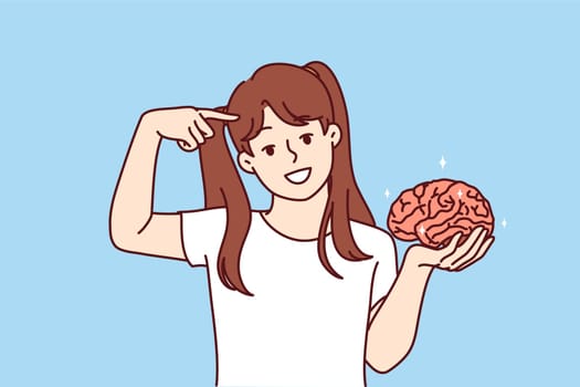 Little girl holds brain in hand and points finger at head, calling to develop intelligence and take care of increasing iq. Smart child with high iq for advertising childrens educational courses