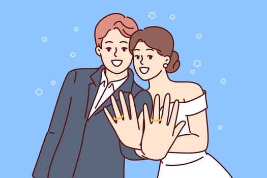 Marriage ceremony of man and woman, with wide smile showing wedding rings on fingers. Loving couple of guy and girl experience romantic feelings, pose after registering wedding or family union