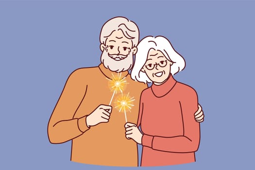 Happy pensioners with sparklers symbolizing christmas stand in embrace together celebrating winter new year holidays. Cheerful gray-haired man and woman using sparklers at festive christmas party