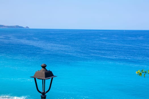 A street lantern over a beautiful blue sea or ocean landscape on the beach coastline blue water with copy space for holiday advertising. Coast of Tyrrhenian Sea.