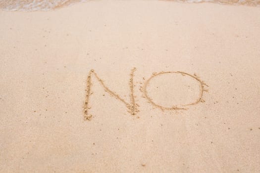 NO sign written in sand on beach texture sunny background. Closeup.