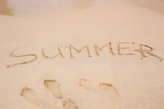 the word summer written in sand on the beach