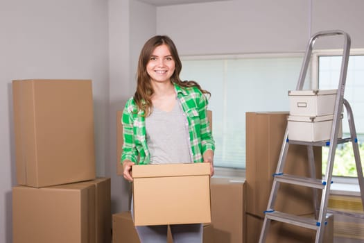 Beautiful young woman holding a cardboard box. Ready for moving. Moving in a new apartment