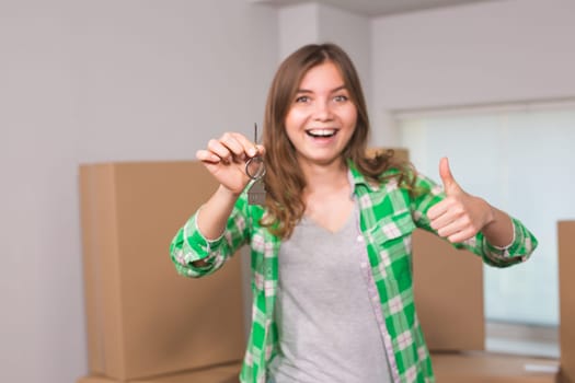 Happy apartment owner or renter showing keys and making thumbs up gesture.