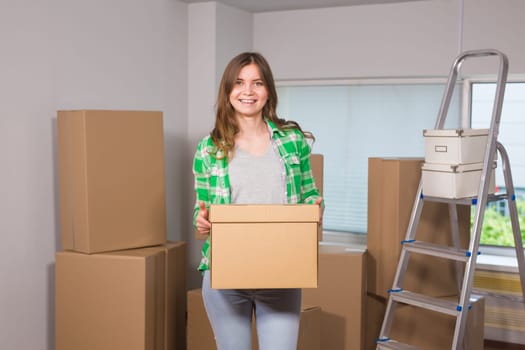 Beautiful young woman holding a cardboard box. Ready for moving. Moving in a new apartment