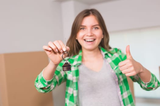 Happy apartment owner or renter showing keys and making thumbs up gesture.
