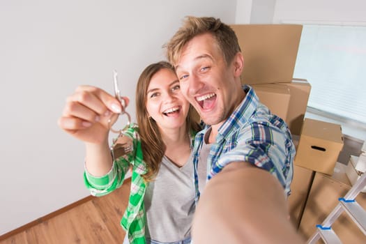 Young married couple with boxes and holding flat keys