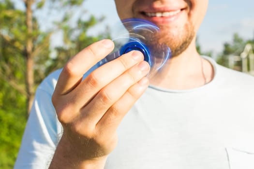Close up of man playing with a blue hand spinner fidget toy.