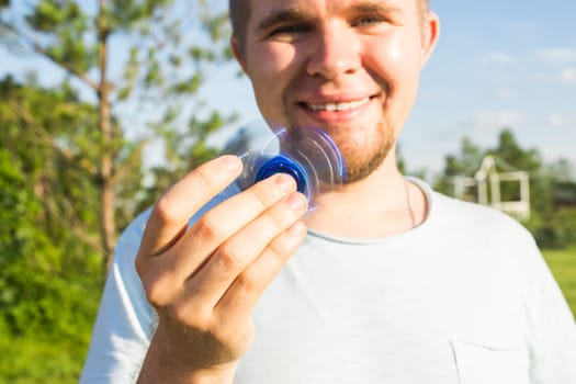 young man playing with a fidget spinner, focus on spinner