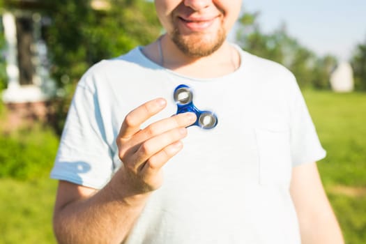 Man playing with a blue spinner fidget toy, close up.