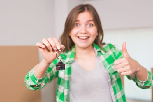 Happy apartment owner or renter showing keys and making thumbs up gesture.