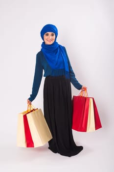portrait of asian muslim woman with shopping bags on white background.