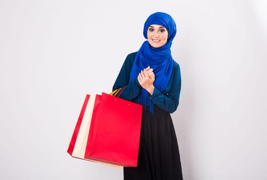 Happy young muslim woman with shopping bag on white background.
