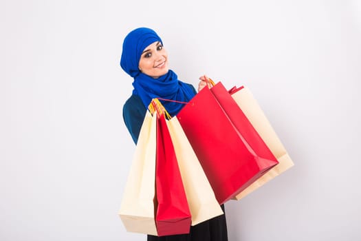 Happy young muslim woman with shopping bag on white background.