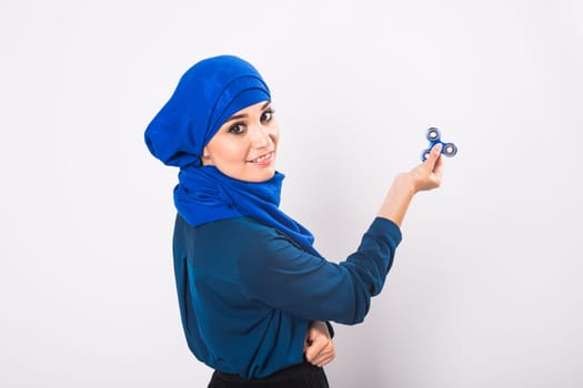 Young beautiful muslim girl holding and playing with fidget spinner. Studio shot on white background.