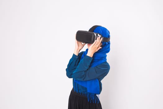 Asian muslim woman wearing hijab using VR headset glasses of virtual reality on white background